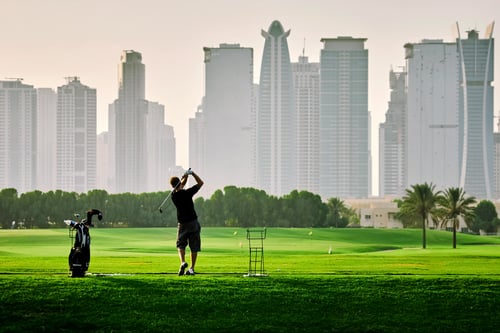 A person playing golf with the Dubai skyline in front of him