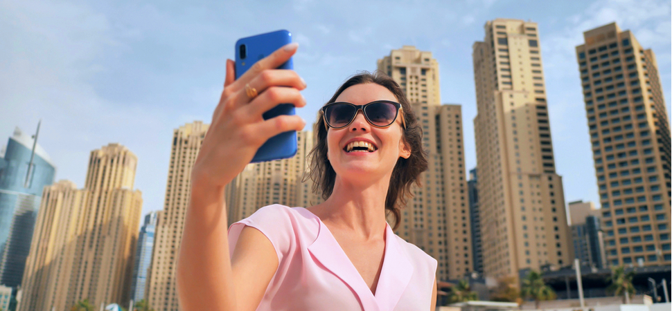 Woman holding smartphone in Dubai, broadcasting live on social media